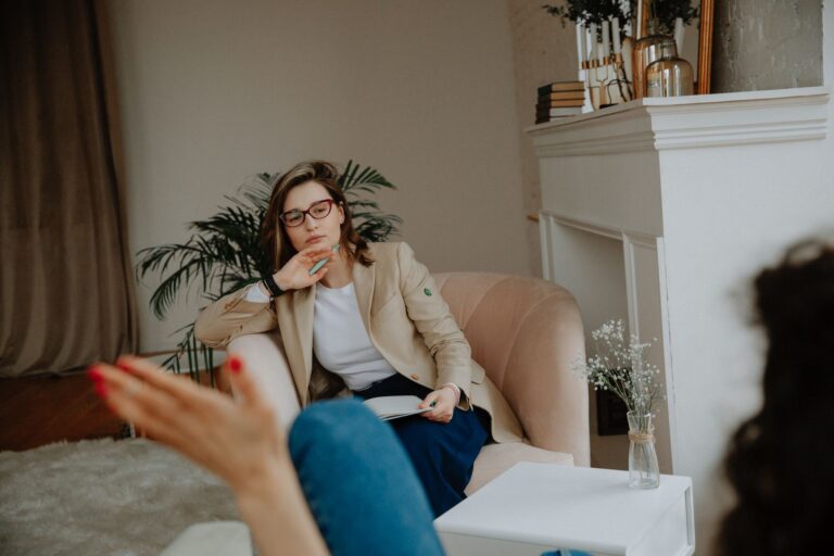 A woman counselor attentively listens during a therapy session in a cozy office environment.