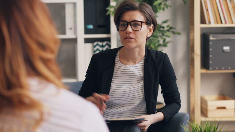 A professional therapist in a modern office setting engaged in a discussion with a client.