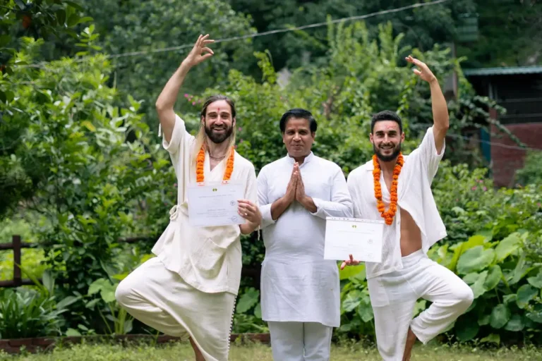 Yoga graduates celebrating certification with instructor in Rishikesh, India.