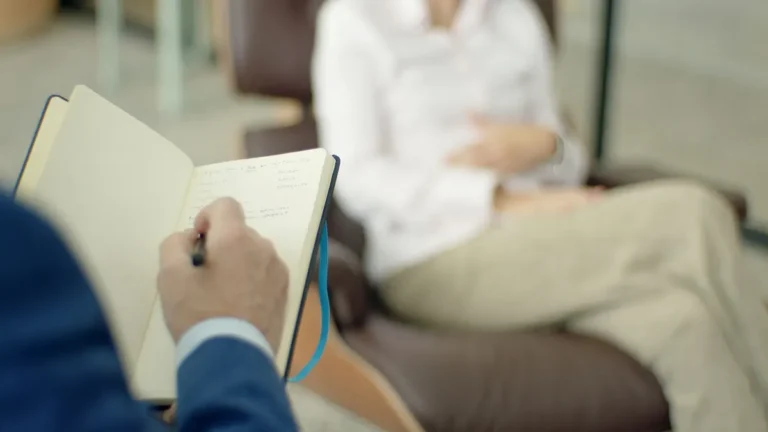 Therapist writing notes during a counseling session with a client.