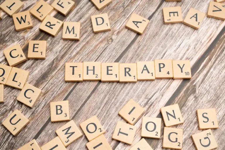 Wooden letter tiles spelling 'therapy' on a wooden background, emphasizing mental health.