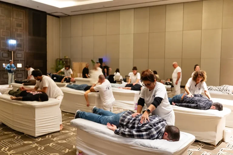 Group of therapists providing massages at an indoor wellness session.